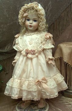 a doll that is wearing a dress and bonnet on it's head, standing in front of a chair