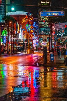 people are walking down the street at night with umbrellas and neon signs in the background