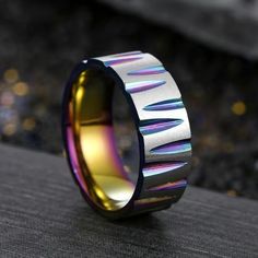 a colorful ring is sitting on top of a black surface with gold and silver inlays