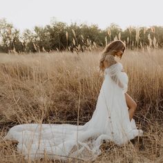 a woman in a white dress is walking through tall grass