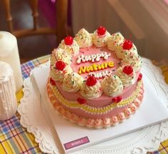 a pink cake with white frosting and sprinkles sitting on top of a table