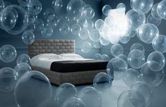 a bed with lots of bubbles floating around it in a room filled with blue walls