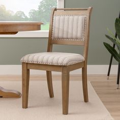 a wooden chair sitting on top of a rug in front of a desk and window