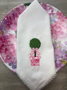 a pink and white plate with a flower pot on it, next to a napkin