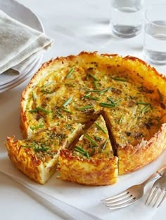 a quiche on a plate with a fork and glass of water in the background