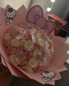 a bouquet of roses with hello kitty stickers on the top and pink tissue paper around it