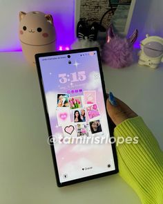 a person holding an iphone in their hand with pictures on the screen and pink lights behind them