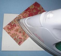 a white iron sitting on top of a piece of paper next to a red and gold cloth