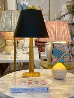 a table with two lamps on it and a book sitting on top of the table