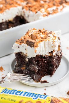 a piece of chocolate cake on a plate with a fork and candy bar in the background