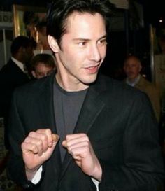 a man wearing a suit and tie standing in front of a group of other people