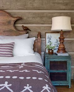 a bed with two lamps on either side of it and a wooden headboard in the background