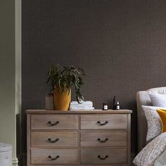 a bedroom with a bed, dresser and potted plant