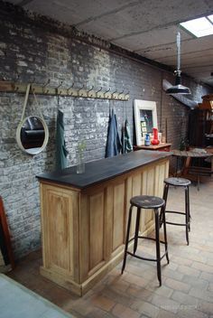 a bar with stools next to it in front of a brick wall