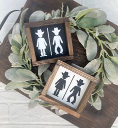 two framed silhouettes are sitting on a table next to some green leaves and branches