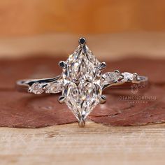 a diamond ring sitting on top of a piece of wood next to a wooden surface