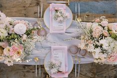 the table is set with pink and white flowers, silverware, and napkins