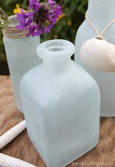 three glass vases sitting on top of a wooden table