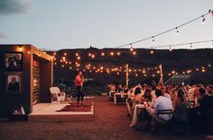 people sitting at tables with lights strung over them