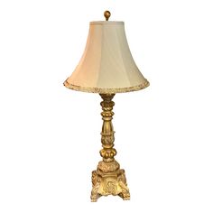 a gold lamp with a white shade on it's base and an ornate design