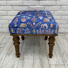 a blue ottoman sitting on top of a wooden floor next to a white brick wall