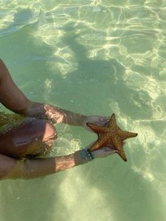 a woman sitting in the water holding a starfish