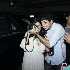 a man taking a photo with a woman in front of a car at night time