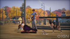 a man playing guitar with two dogs and cats in front of him on the boardwalk