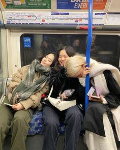 three young women sitting on a subway train