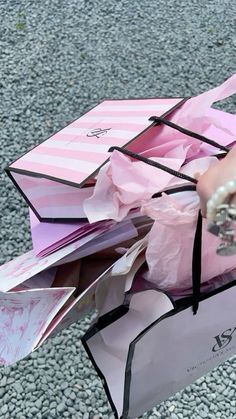 a person holding a pink paper bag full of cards and envelopes on the ground