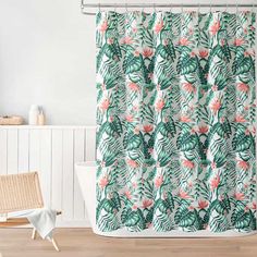 a shower curtain with pink and green tropical leaves on it in a white bathroom next to a bathtub