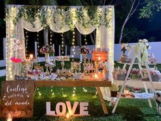 a table topped with lots of desserts and candles next to a sign that says love