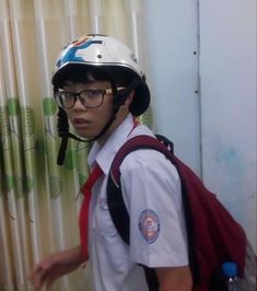 a young boy wearing a helmet and carrying a backpack