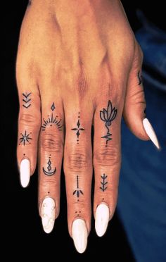 a woman's hand with tattoos on it and an arrow, lotus, and sun