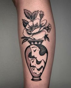 a black and white photo of a vase with flowers on the side of a woman's leg