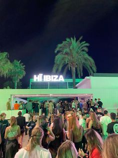 a crowd of people standing around in front of a building with a sign that reads hi ibiza