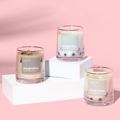 three candles sitting on top of each other in front of a pink background and white box