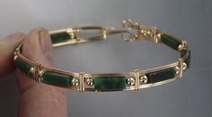 ELEGANT HIGH FASHION GREEN JADE  GEMSTONE BANGLE BRACELET IN  14kt rolled gold  THESE ARE ROUND TUBULAR STONES  HANDCRAFTED IN 14kt rolled gold  IN A UNIQUELY DESIGNED SETTING UNIQUE HANDCRAFTED PIECE THAT WILL GET YOU NOTICED! LIGHTWEIGHT AND EASY TO WEAR SIZE ----- SIZE 6 TO 8 BRACELET IS  1/2 WIDE iTS COMFORTABLE HEAVY DUTY HOOK AND CATCH MAKES IT EASY TO TAKE ON AND OFF AN EYE CATCHING PIECE! WEAR IT CASUAL OR FORMAL OUR GEMSTONES ARE AAA HIGH GRADE  JADE ABOUT MY JEWELRY This is wire sculpt Green Jewelry Gold, Jade Bangle Stack, Gold Bangles With Stones, Gold And Jade Bracelet, Green Jewelry Aesthetic, Green Jeweled Bangle Bracelet, Gold And Green Jewelry, Elegant Gold Jade Bracelets, Green And Gold Jewelry