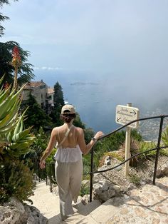 a woman walking up some stairs towards the ocean