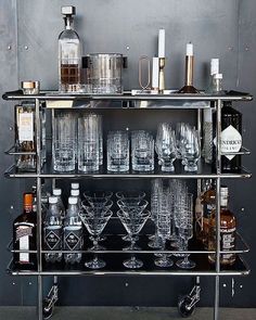 a metal bar cart filled with glasses and bottles