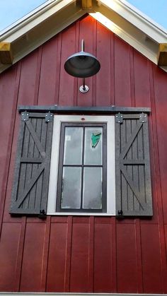 a red barn with an open window and black shutters