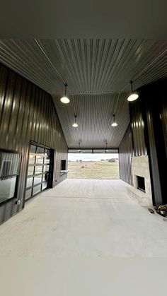 an empty parking garage with two doors and lights hanging from the ceiling, in front of a large open area