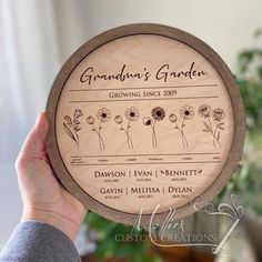 a person holding up a wooden plaque with flowers on it's front and side