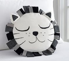 a white pillow with a black and grey lion design on it's face, sitting on a bed