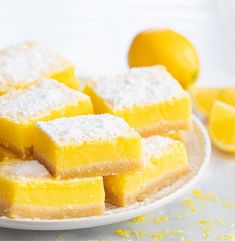 several pieces of yellow cake sitting on top of a white plate covered in powdered sugar