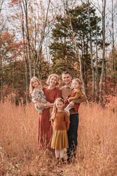 a family posing for a photo in the middle of a field with tall grass and trees