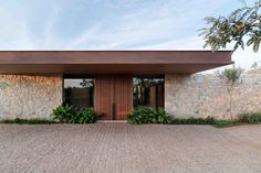 the entrance to a modern home with stone walls and brick walkway leading up to it