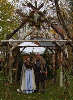 two people dressed in medieval costumes under a gazebo