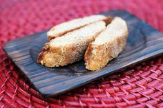 two pieces of bread sitting on top of a wooden plate next to a red tablecloth