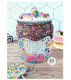 a jar filled with lots of sprinkles next to a lollipop